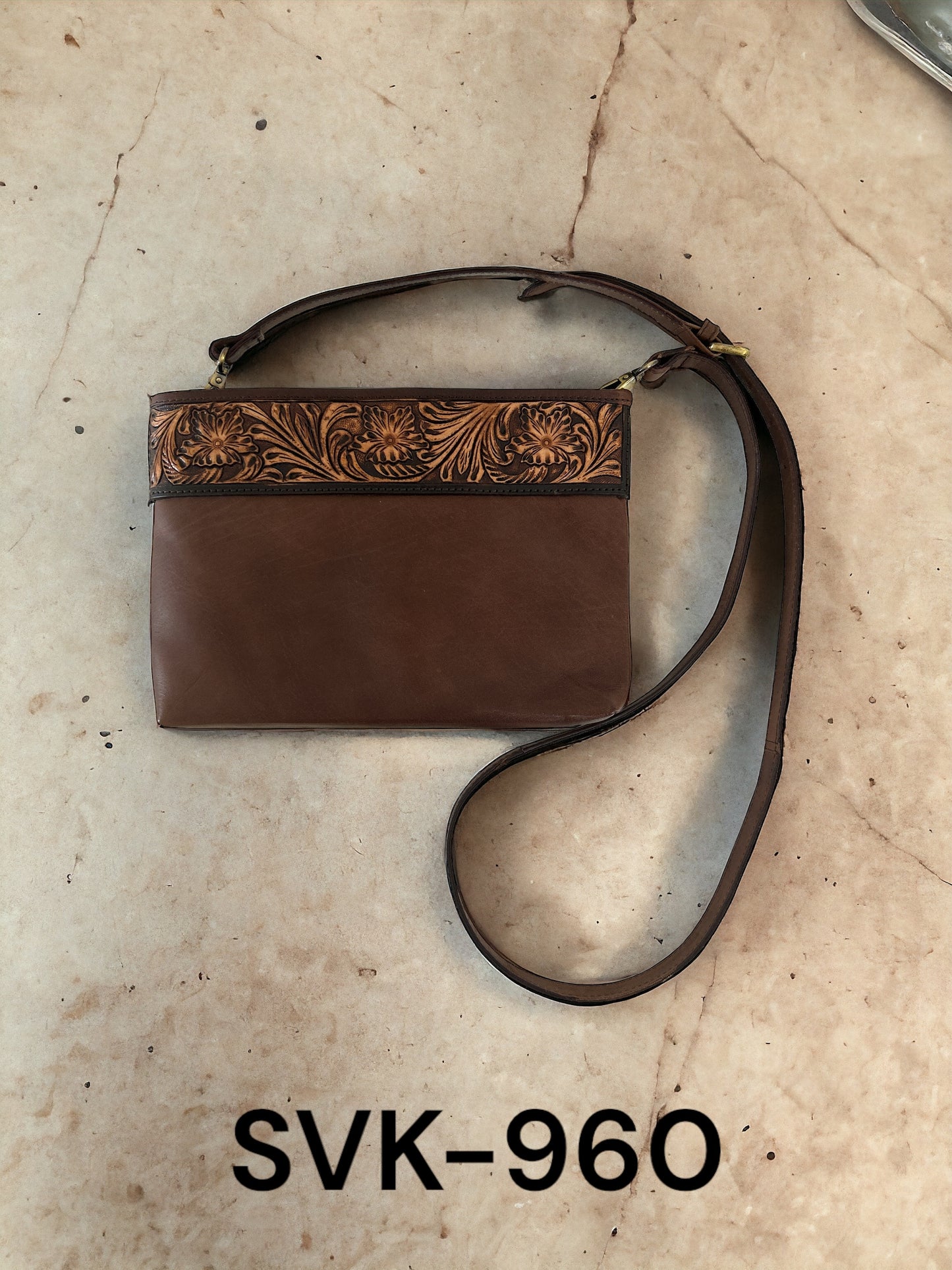 Brown leather handbag with floral embossing on a beige surface, labeled SVK-960.